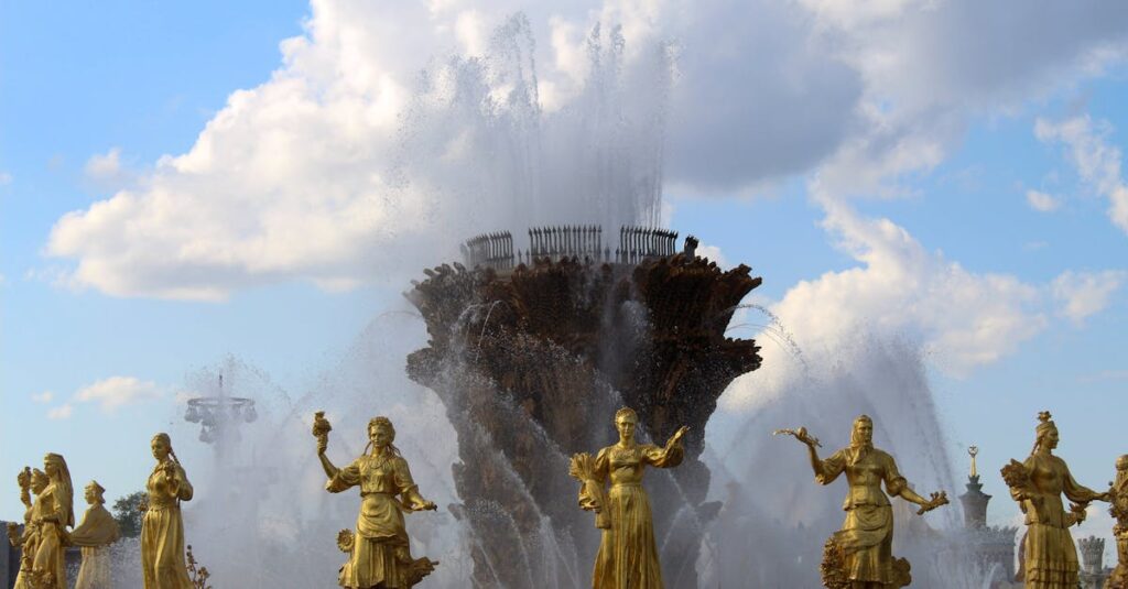 Stunning fountain with golden statues under a blue sky at VDNKh, showcasing artistic craftsmanship.